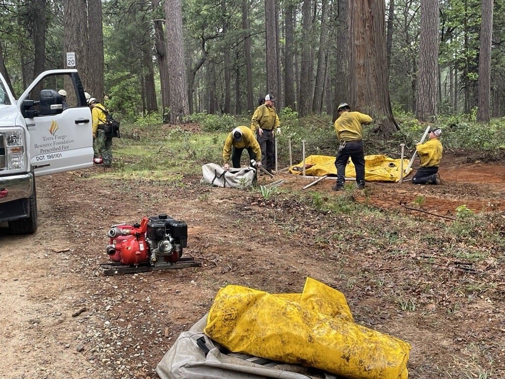 Crew unloading a portable fire pump and hose bundles from the Terra Fuego truck before ignition.