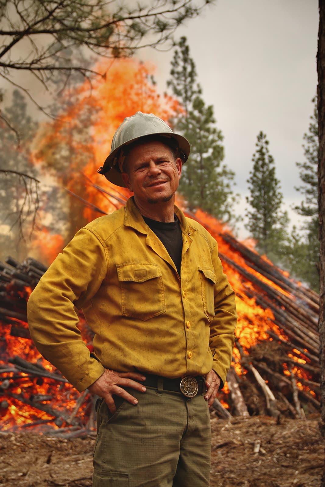 A firefighter in front of a fully involved machine pile.