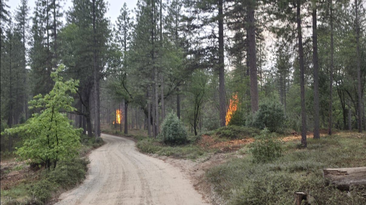 Two piles glowing and smoldering next to the road, seen from a distance.